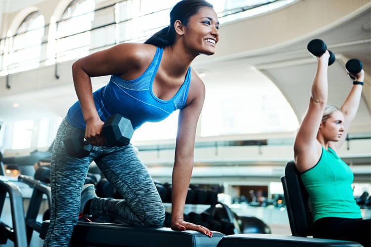 woman in workout clothing lifting a weight at a fitness center