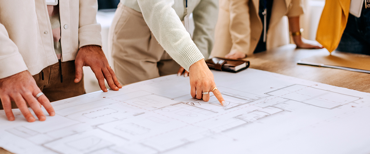 Cropped image of hands pointing to a blueprint