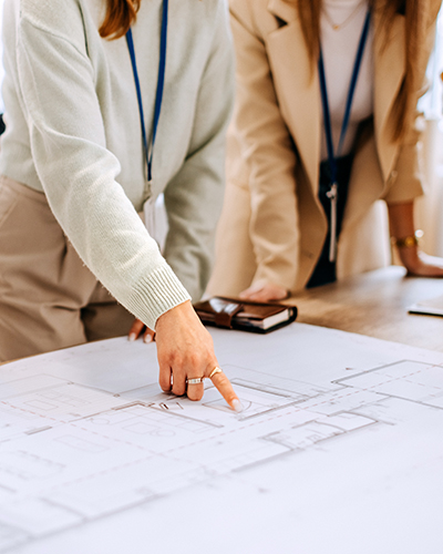 Cropped image of hands pointing to a blueprint
