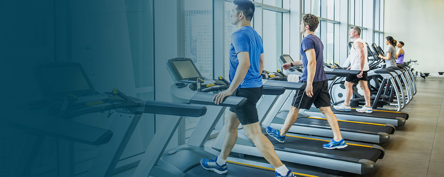 People exercising on stationary fitness equipment in a corporate fitness center.